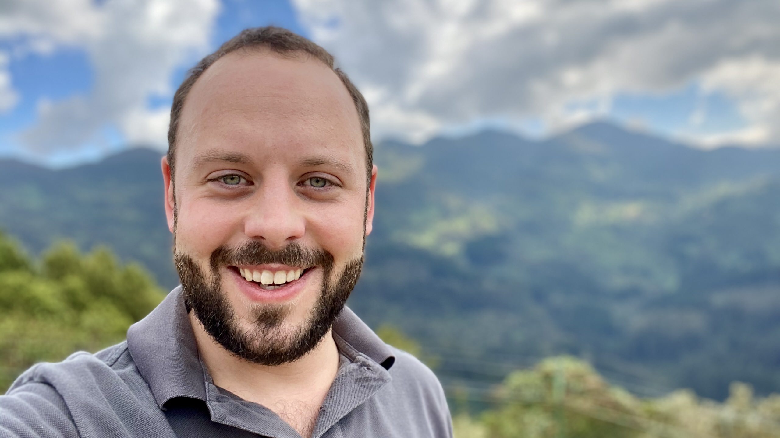 Julian Besken im Freien, Berge und Wolken im Hintergrund